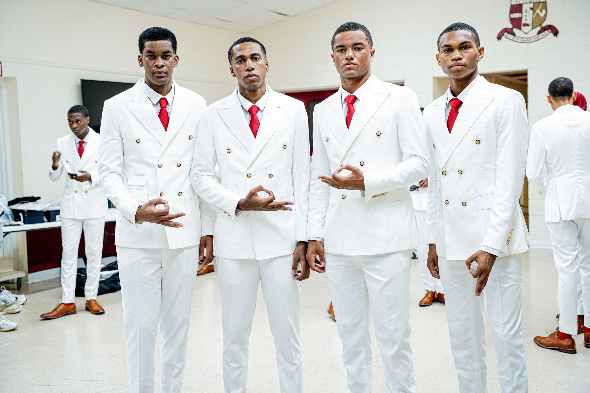 Four members of SWIFT 22 in white double-breasted suits and crimson ties