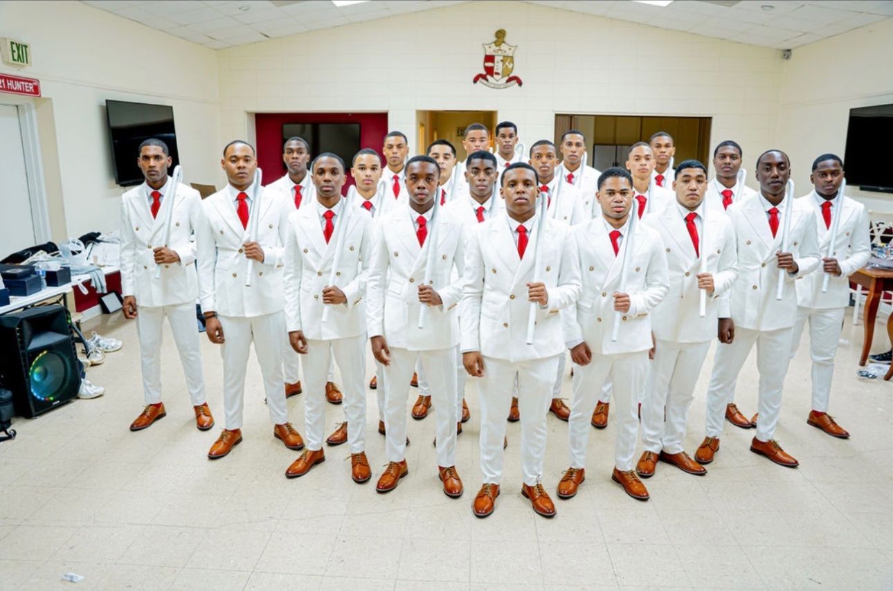The members of SWIFT 22 gathered together in white suits and crimson ties beneath the chapter crest