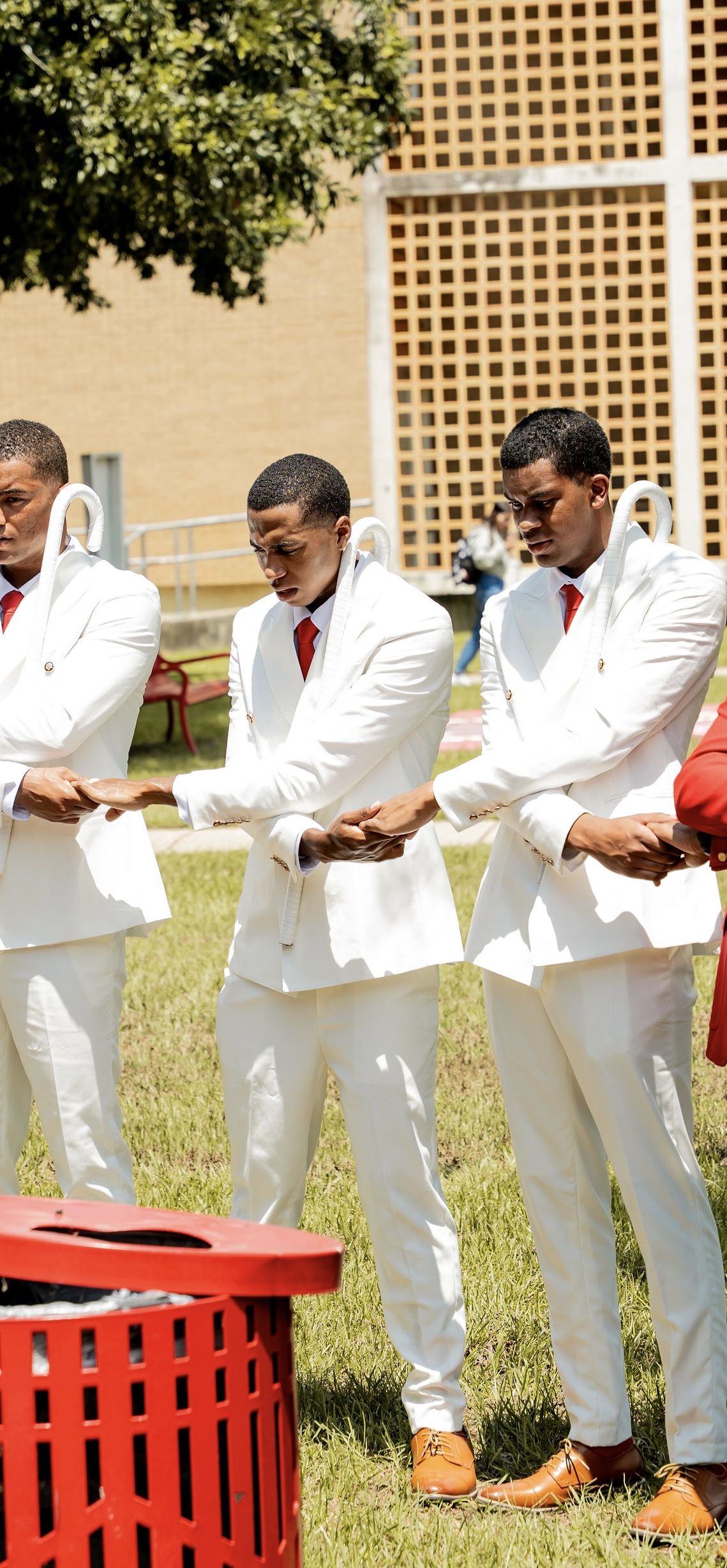 Brothers in white suits with arms linked on the yard