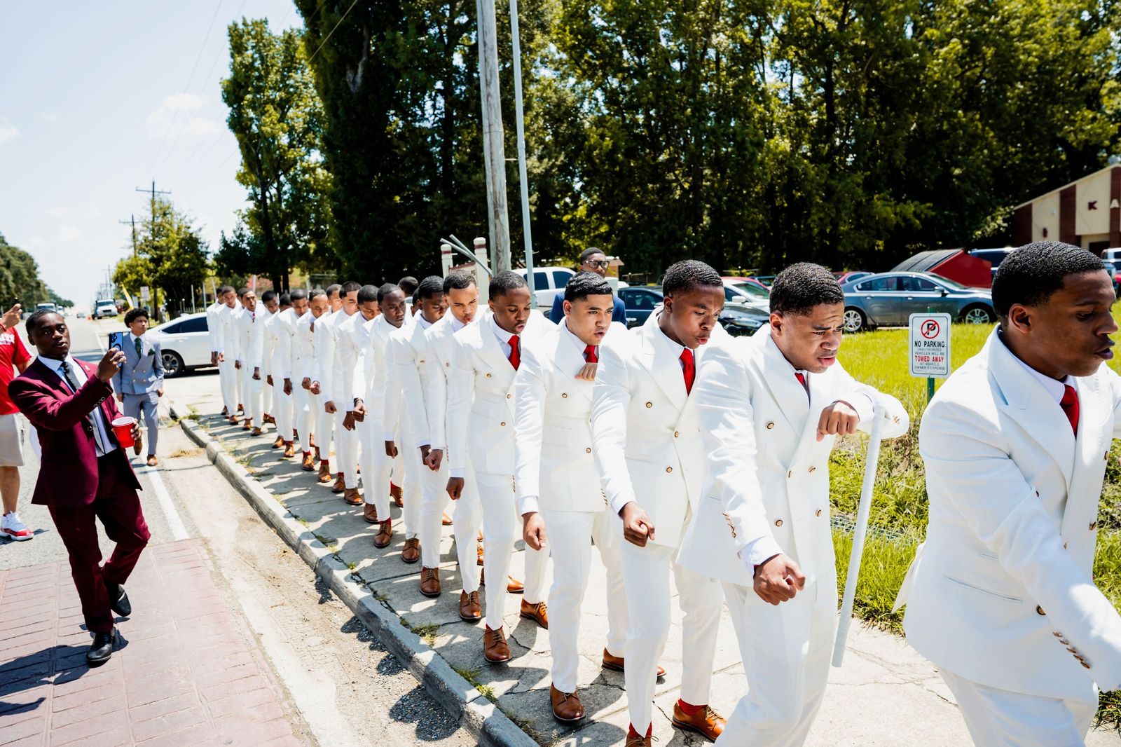 The line marching single file down the street in white suits